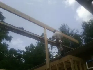 Carpenter setting a ridge beam over a new addition frame — Ice Dam Removal by Roofing Brothers in Eckert