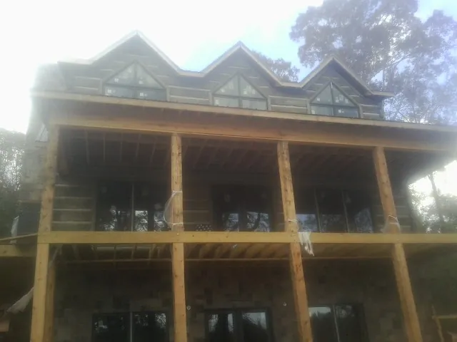 Dormers and porch framing on a large log home under construction — Roof Coating work by our crew in Eckert