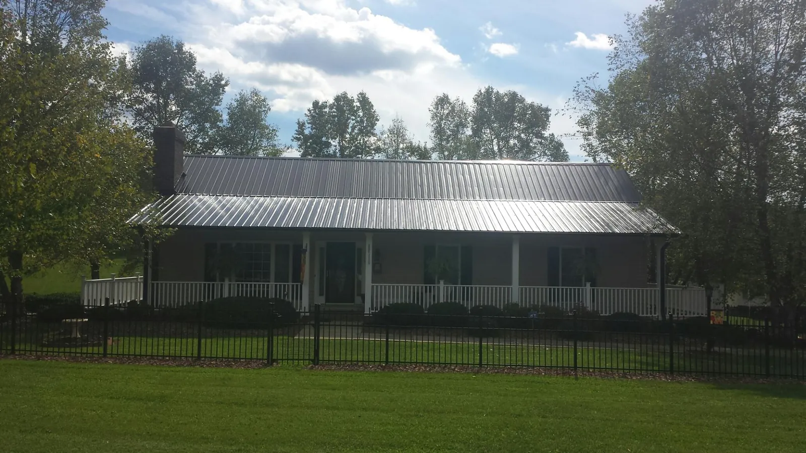 Gray metal roof on a brick ranch with a full width front porch — Gutter Guard Installation work by our crew in Eckert