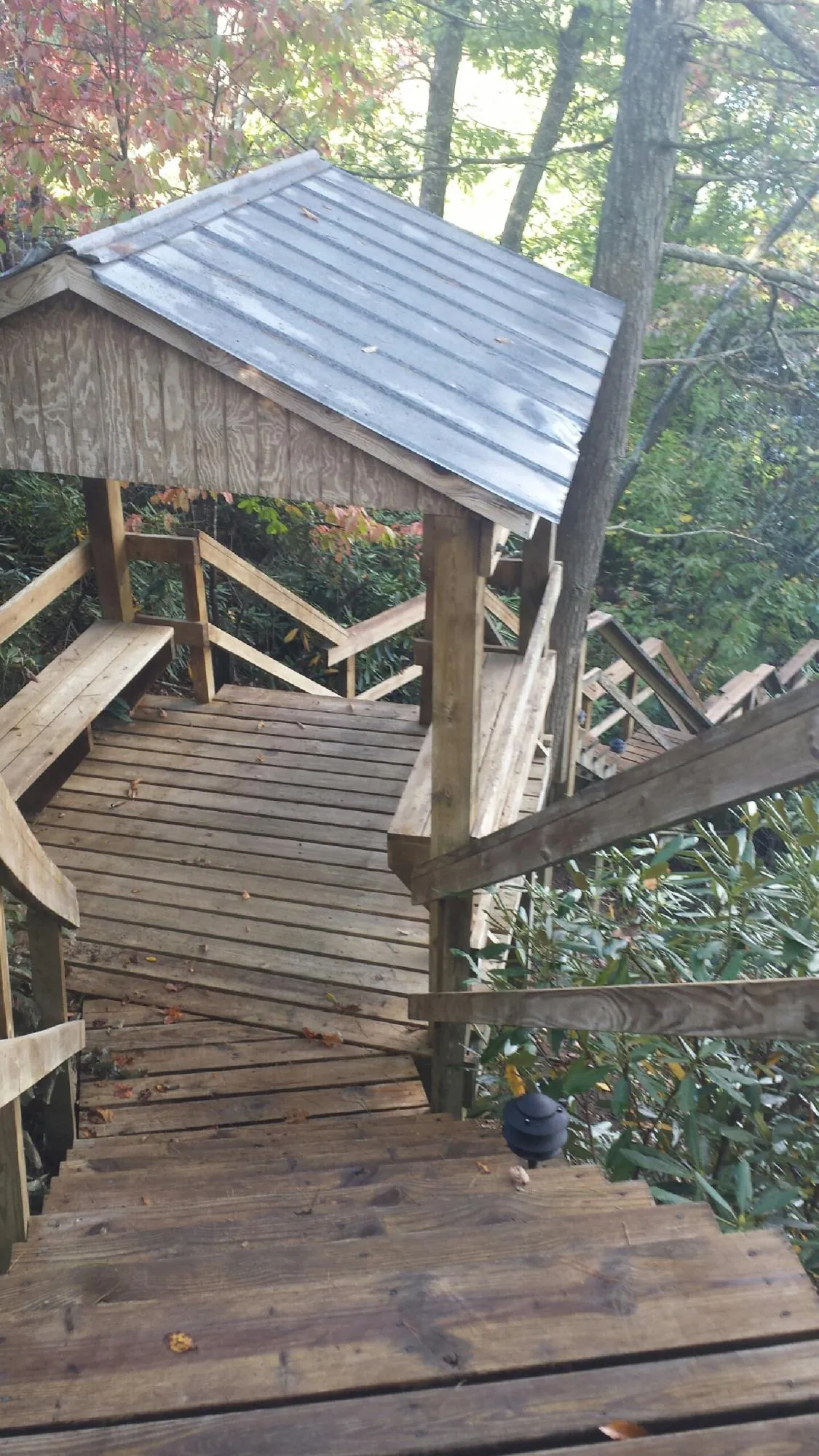Metal roofed shelter over wooden steps on a wooded walkway — Skylight Repair & Installation work by our crew in Eckert