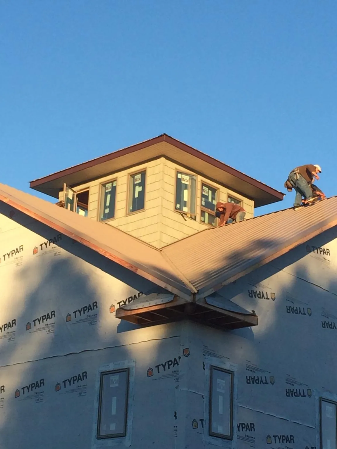 Roofers working around a rooftop cupola on a new metal roof at sunset — Roof Waterproofing in Eckert by Roofing Brothers